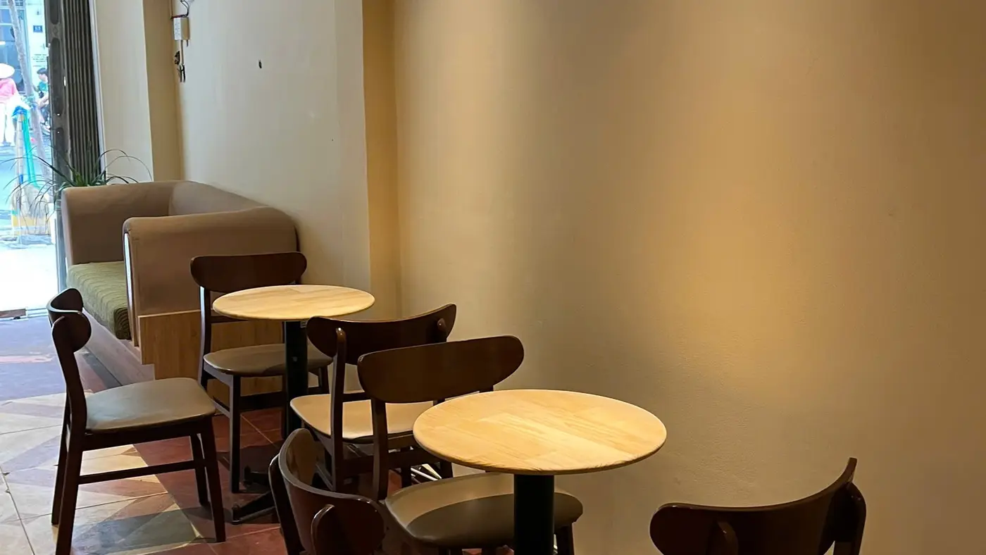 Window-side tables inside Virgin Saigon Original Coffee, District 1, empty and lit for the afternoon.
