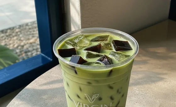 A matcha coffee jelly in a Virgin cup, on the terrazzo table by the blue window frame.