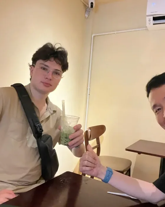 Two guests at a table in the café with a green iced drink and an iced coffee, one giving a thumbs-up.