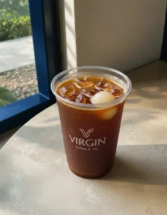 Iced Americano with lychee in the Virgin cup, dark coffee over ice with a peeled lychee floating among the cubes.