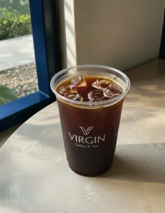 Iced black coffee in the Virgin cup, near-black phin coffee over ice with a thin crema ring.