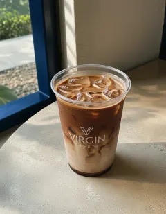 Iced chocolate latte in the Virgin cup, milk marbled with chocolate ribbons over ice, darker chocolate-milk pooling at the base.