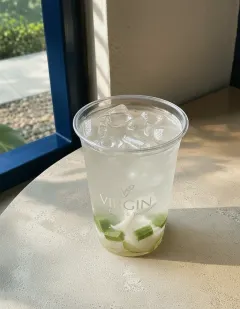 Fresh coconut water with aloe vera in the Virgin cup, near-clear pale coconut water with translucent aloe vera cubes.