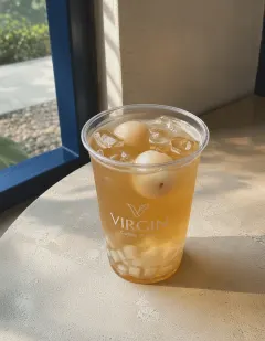 Iced lychee tea with jelly in the Virgin cup, clear amber tea with peeled lychee and white coconut jelly cubes.