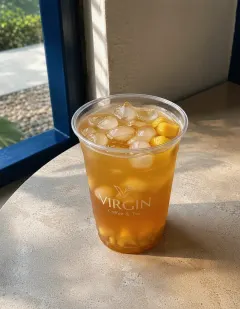 Iced pineapple and palm seed tea in the Virgin cup, clear amber tea with pineapple pieces and đác palm seeds.
