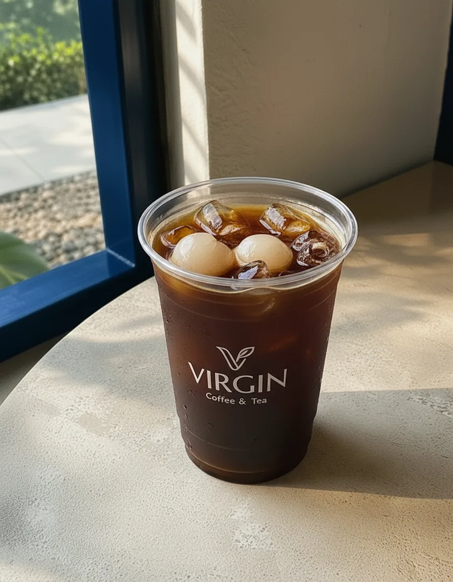 Cold brew coffee with lychee in the Virgin cup, deep near-black coffee over ice with a peeled lychee among the cubes.