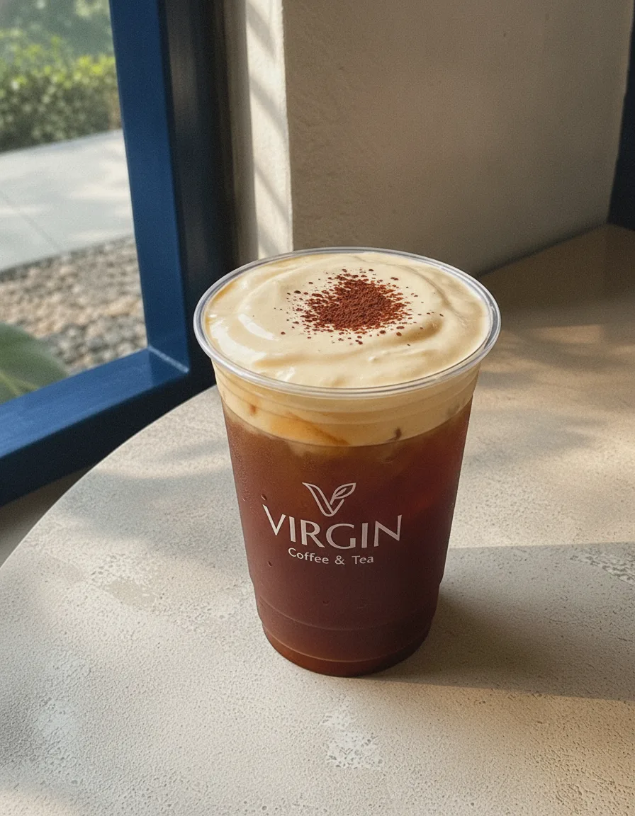 Iced salted coffee in the Virgin cup, dark coffee under a thick ivory salted-cream cap dusted with cocoa.